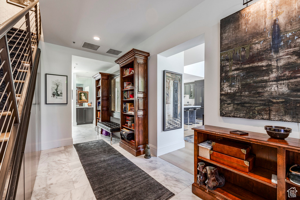 Corridor featuring light marble finish flooring, baseboards, and recessed lighting