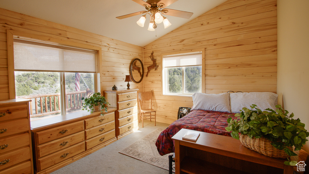 Bedroom featuring lofted ceiling, light colored carpet, wood walls, and ceiling fan