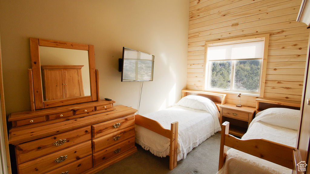 Carpeted bedroom featuring wood walls