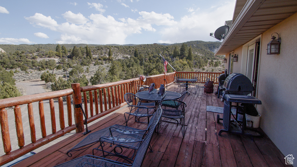 Wooden deck with outdoor dining area, a wooded view, a mountain view, and grilling area