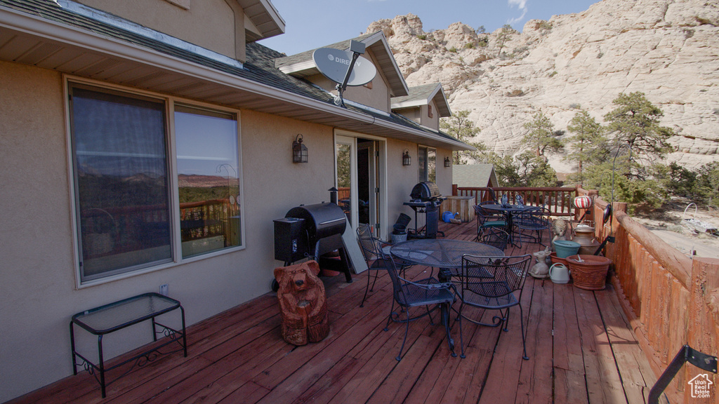 Wooden terrace featuring outdoor dining space, area for grilling, and a mountain view