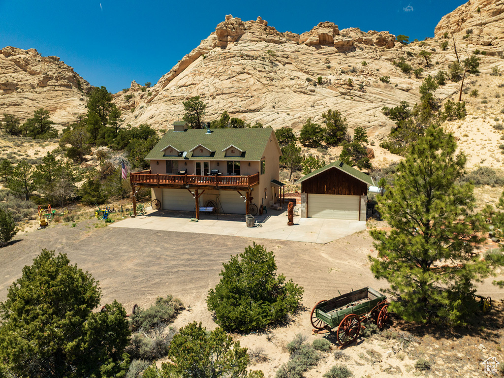 View of front of home with concrete driveway and a deck with mountain view