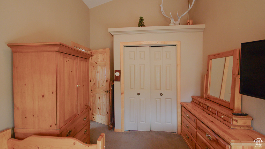 Unfurnished bedroom featuring carpet floors, lofted ceiling, and a closet
