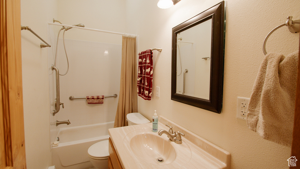 Bathroom featuring toilet, shower / bath combo, and vanity