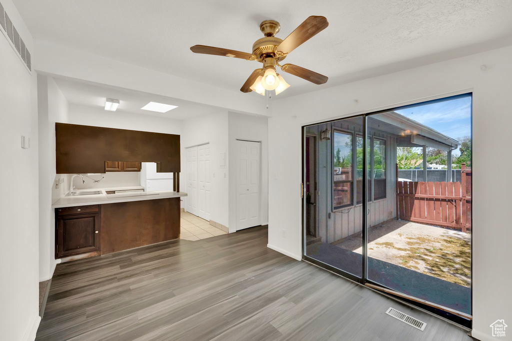 Unfurnished living room featuring light wood-type flooring, ceiling fan, baseboards, and a sink