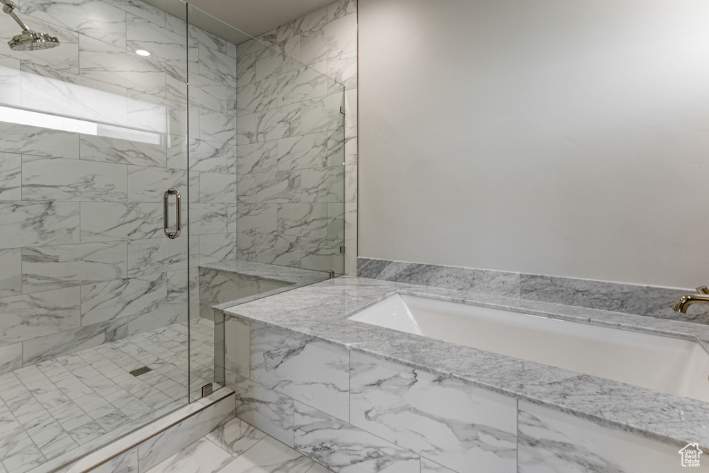 Bathroom featuring a marble finish shower, a garden tub, and marble look tile flooring