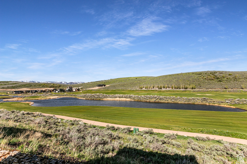 View of home's community with a water and mountain view, golf course view, and a yard