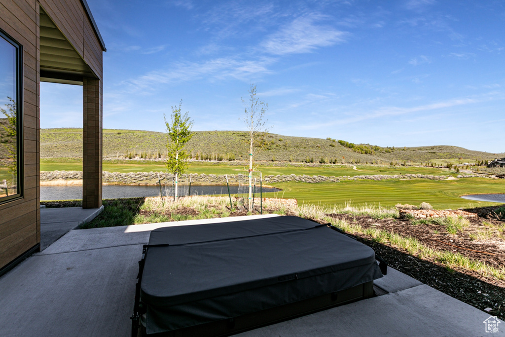 View of patio / terrace with a covered hot tub, view of golf course, and a water and mountain view