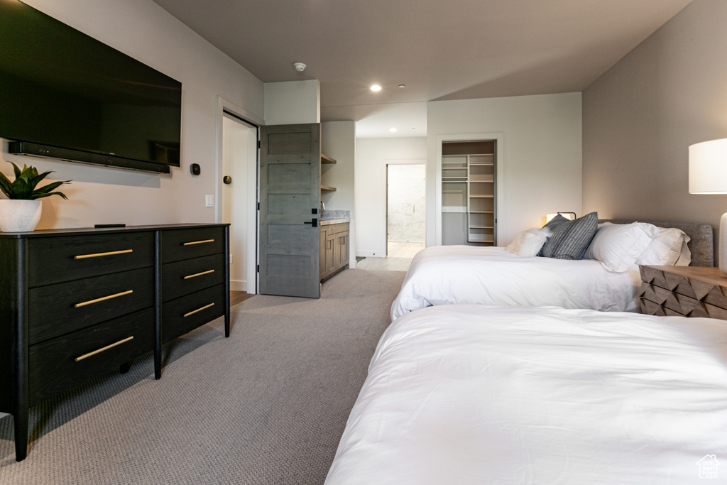 Bedroom with light carpet, recessed lighting, connected bathroom, and a walk in closet