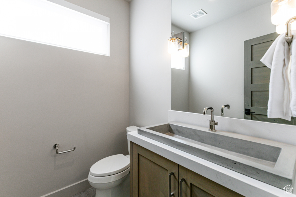 Half bath with plenty of natural light, toilet, vanity, and baseboards