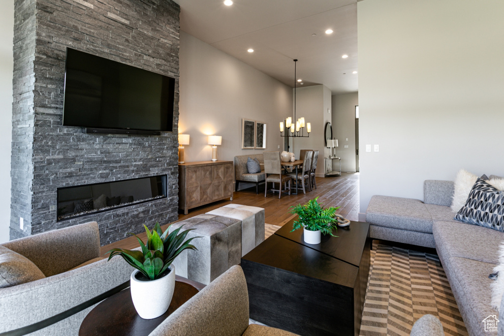 Living area with wood finished floors, recessed lighting, a chandelier, and a fireplace