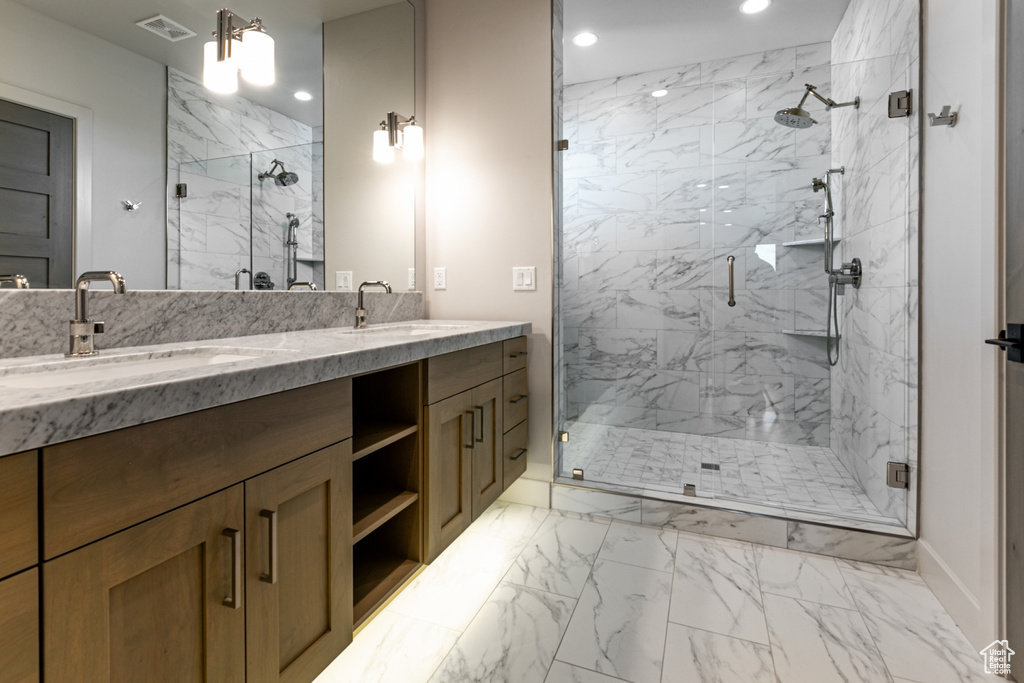 Bathroom with recessed lighting, marble look tiles, a marble finish shower, double vanity, and baseboards