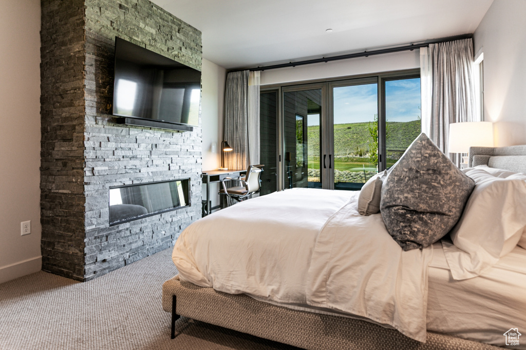 Carpeted bedroom featuring access to exterior and a stone fireplace