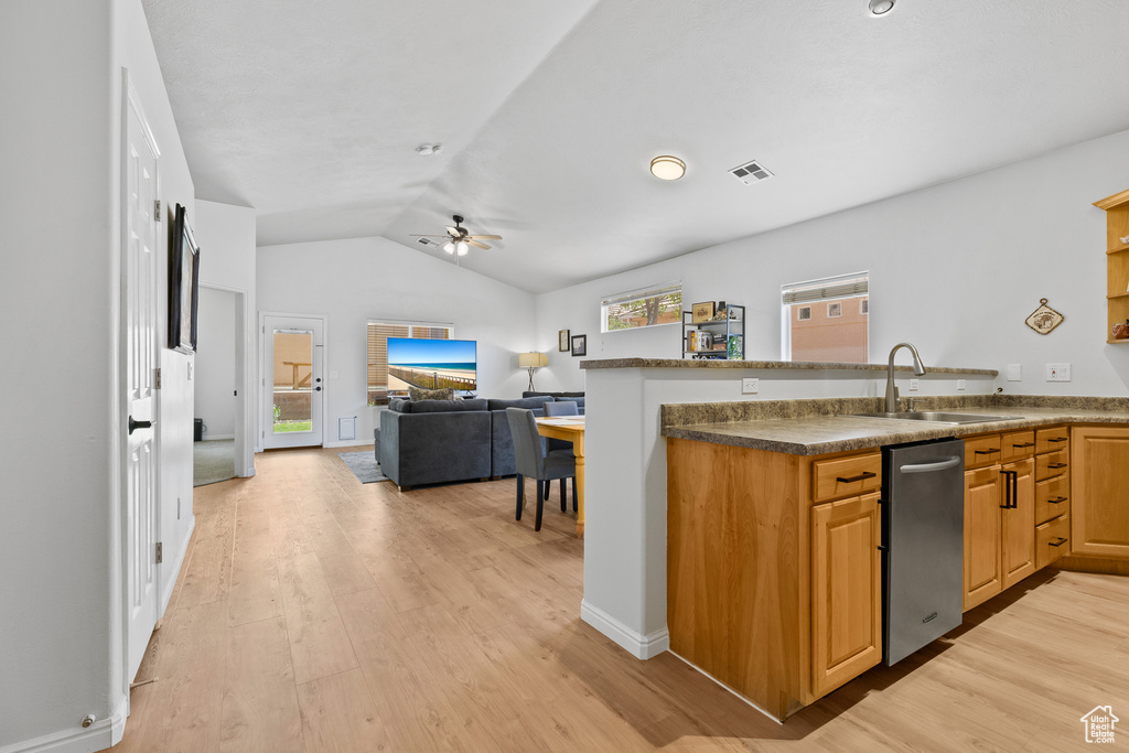 Kitchen with a sink, ceiling fan, light wood finished floors, lofted ceiling, and a peninsula