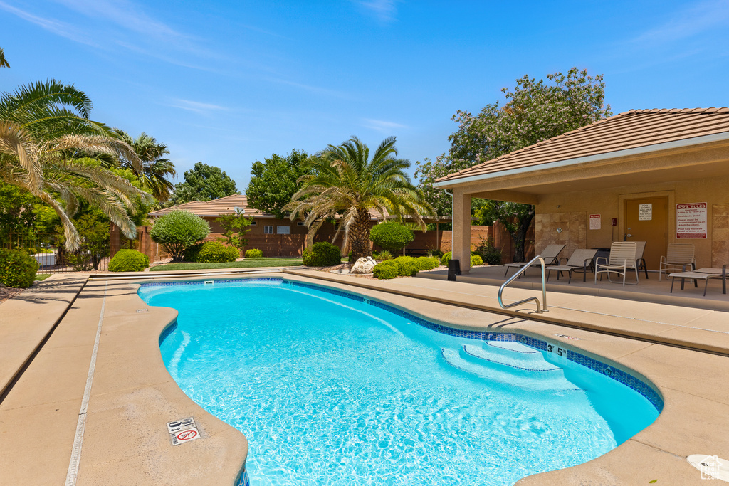 Community pool featuring a patio area and fence