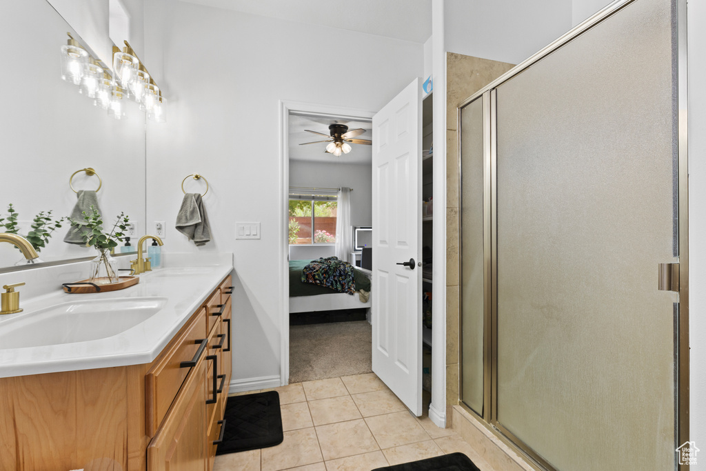 Ensuite bathroom featuring tile patterned flooring, a stall shower, double vanity, ceiling fan, and baseboards