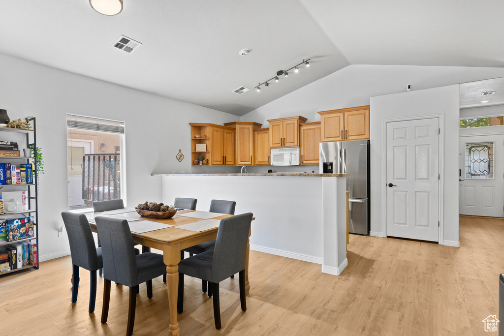Dining area with vaulted ceiling and light wood-style flooring