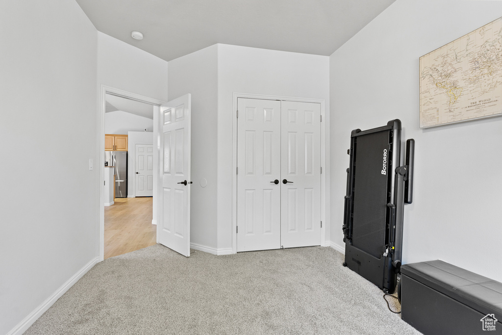 Unfurnished bedroom featuring freestanding refrigerator, carpet flooring, baseboards, and a closet
