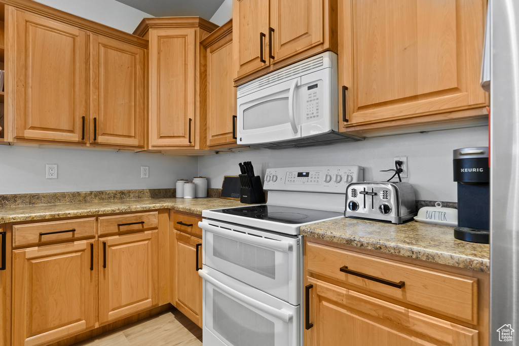 Kitchen with white appliances and light wood finished floors