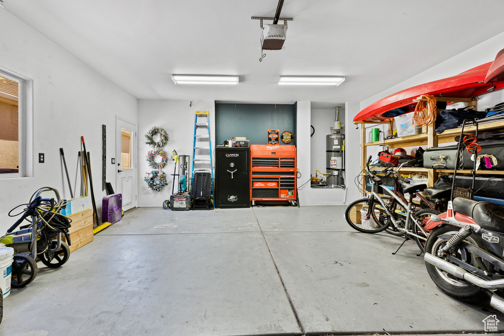 Garage with strapped water heater and a garage door opener