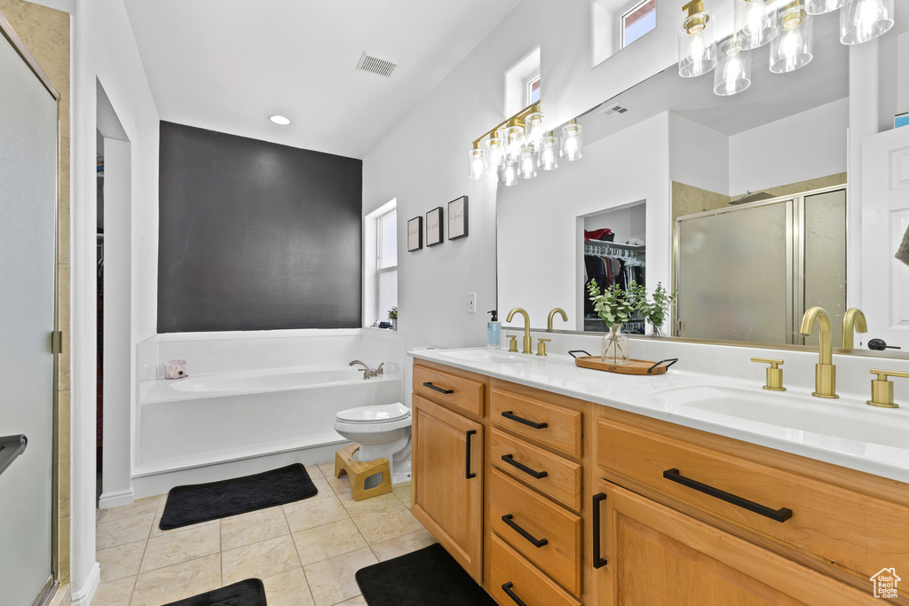 Bathroom with a shower stall, tile patterned floors, a bath, double vanity, and a walk in closet