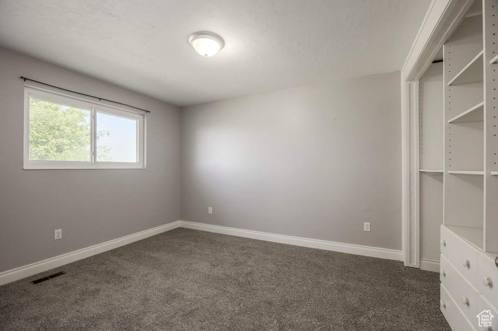 Empty room featuring dark colored carpet and baseboards