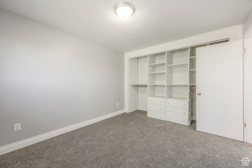 Unfurnished bedroom with carpet, a closet, and baseboards