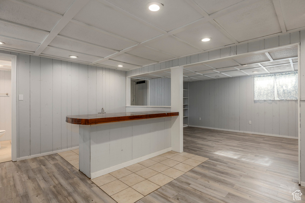 Bar area featuring light wood-style floors, baseboards, recessed lighting, and wood walls
