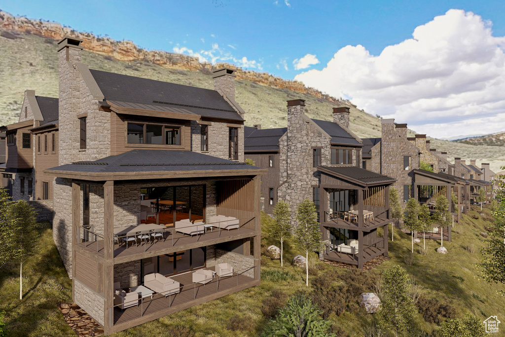 Rear view of property with stone siding, a chimney, a standing seam roof, and a mountain view