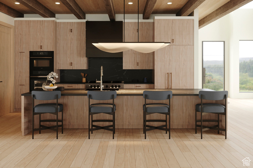 Kitchen with light brown cabinetry, beamed ceiling, a kitchen breakfast bar, light wood-style floors, and recessed lighting