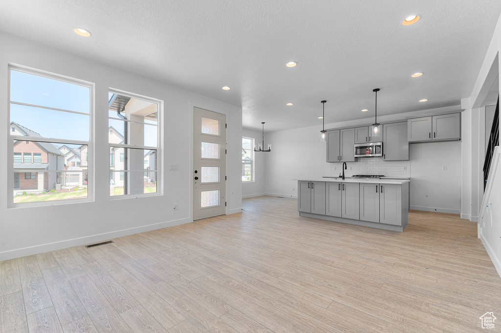 Kitchen with gray cabinets, stainless steel microwave, recessed lighting, baseboards, and light wood finished floors