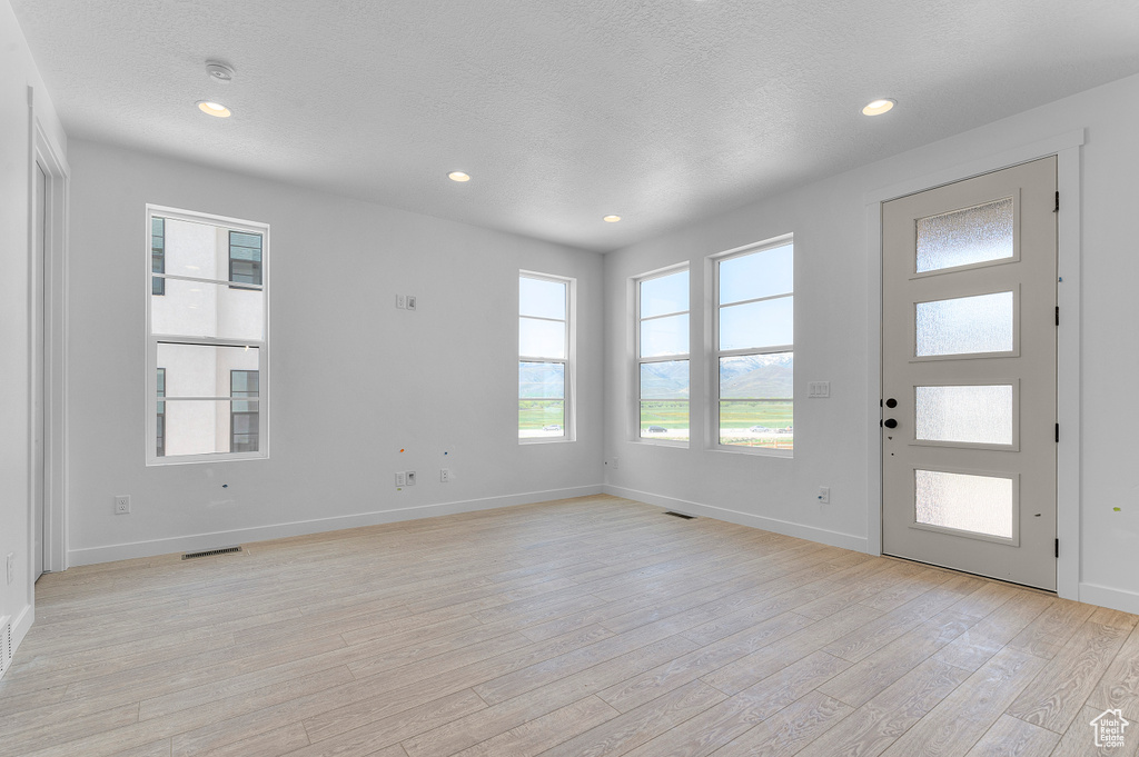 Entryway with light wood-style flooring, plenty of natural light, baseboards, a textured ceiling, and recessed lighting