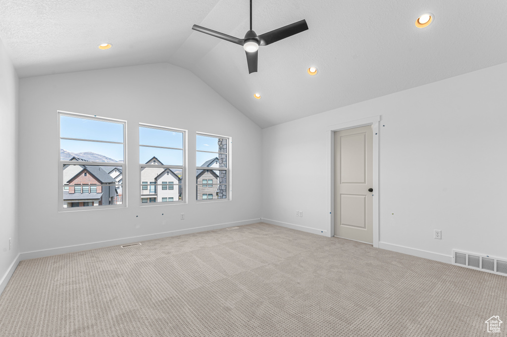 Spare room featuring lofted ceiling, a ceiling fan, light carpet, baseboards, and recessed lighting