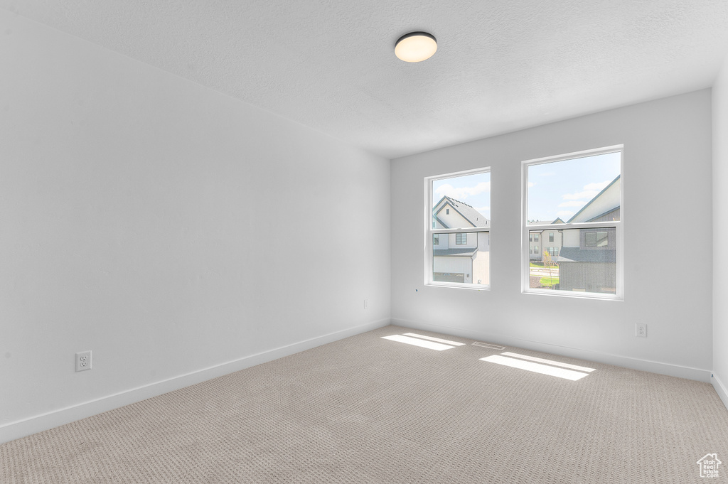 Carpeted spare room with baseboards and a textured ceiling