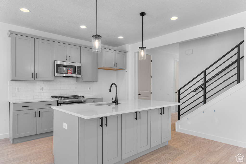 Kitchen with appliances with stainless steel finishes, gray cabinetry, a sink, and recessed lighting