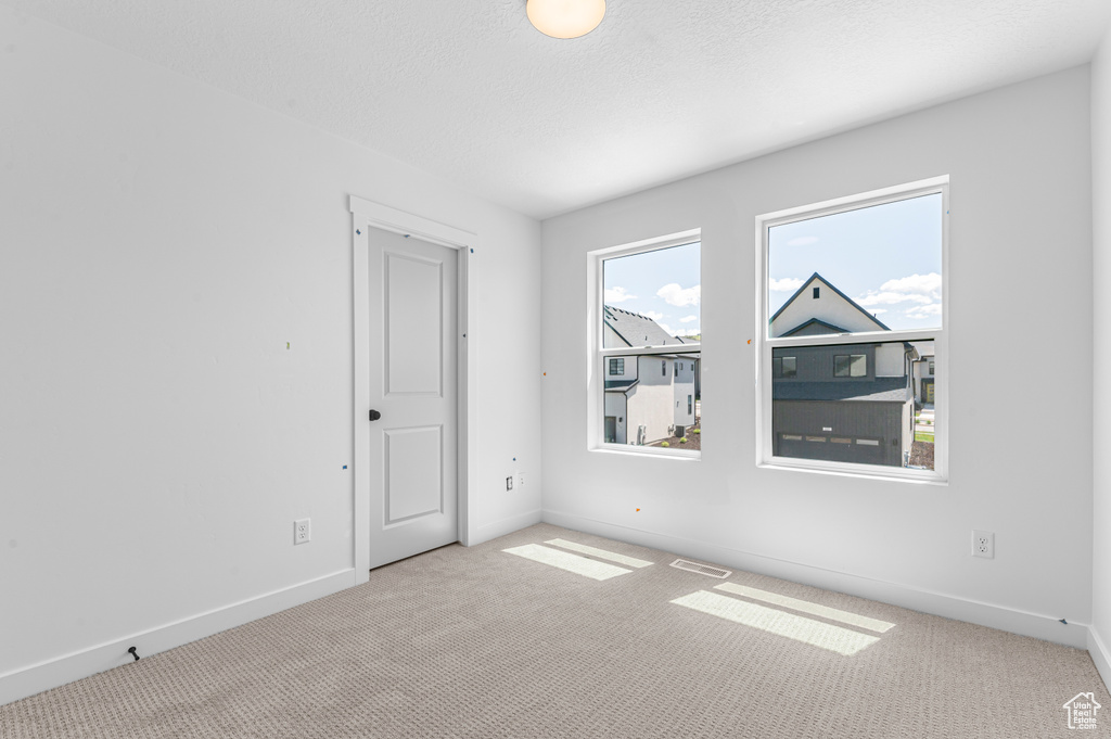 Carpeted spare room with baseboards and a textured ceiling