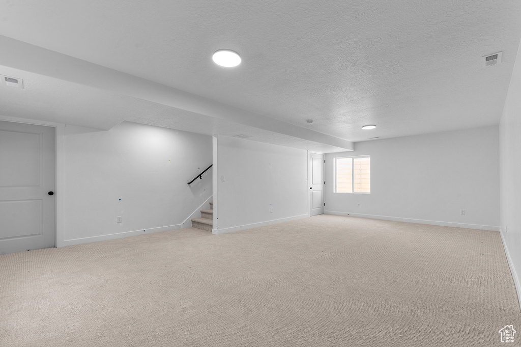 Basement with stairway, baseboards, light carpet, a textured ceiling, and recessed lighting