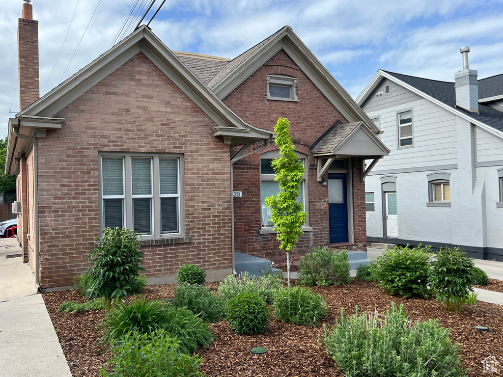 View of front of home featuring brick siding and a chimney