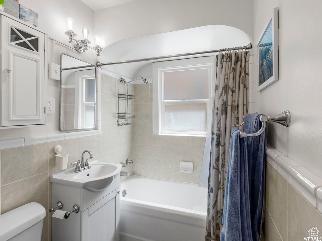 Full bathroom with tile walls, toilet, shower / bath combo, and vanity