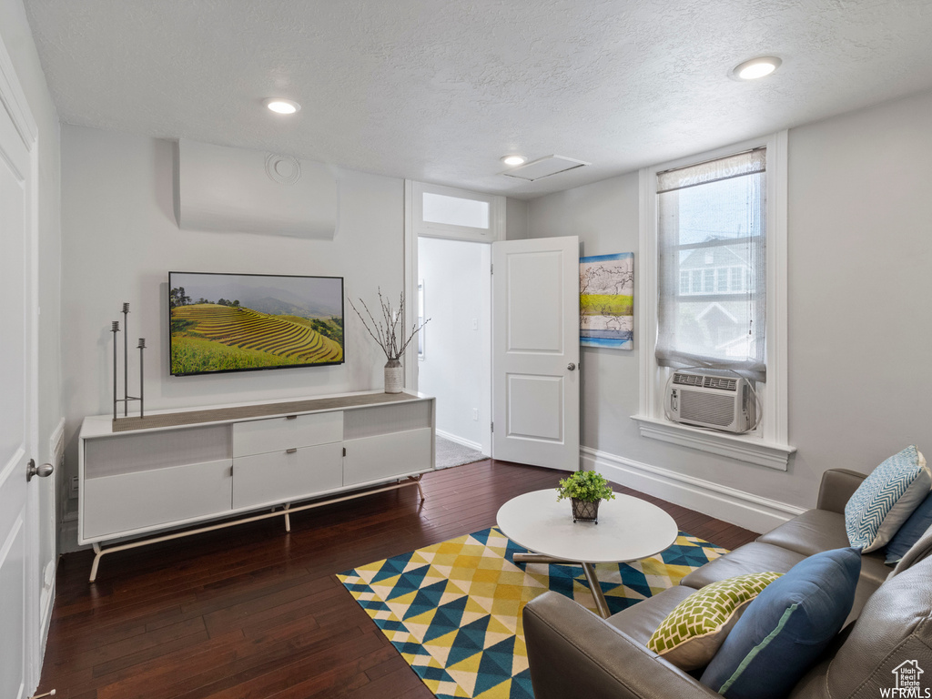 Living area with cooling unit, hardwood / wood-style flooring, a textured ceiling, baseboards, and recessed lighting