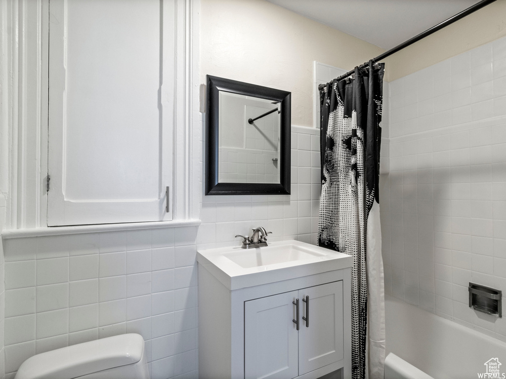 Bathroom featuring tile walls, vanity, shower / tub combo with curtain, and toilet