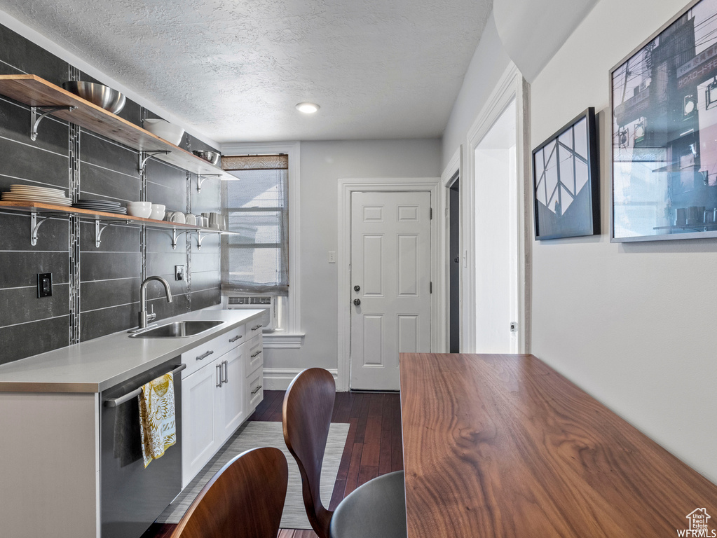 Kitchen with a sink, stainless steel dishwasher, decorative backsplash, white cabinets, and a textured ceiling