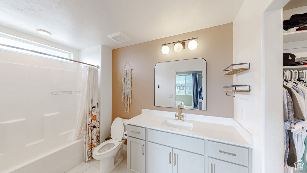 Full bathroom featuring toilet, tile patterned flooring, vanity, shower / bath combo with shower curtain, and a walk in closet