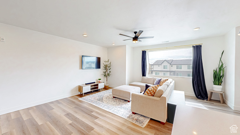 Living room featuring light wood finished floors, a ceiling fan, baseboards, and recessed lighting