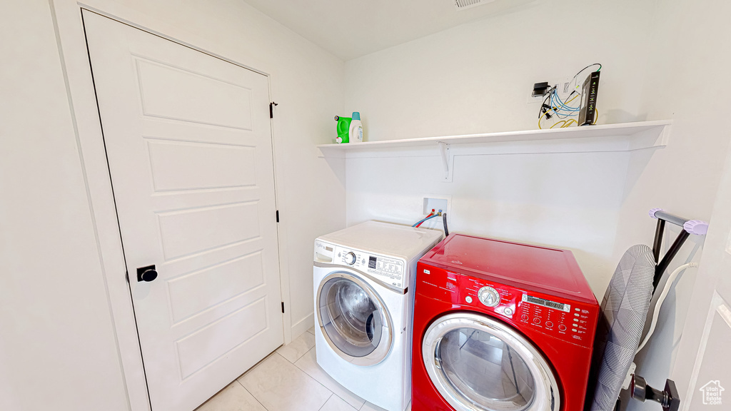Laundry area with washer and clothes dryer and light tile patterned floors