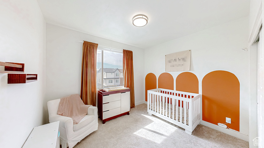 Bedroom with light carpet, a crib, and baseboards