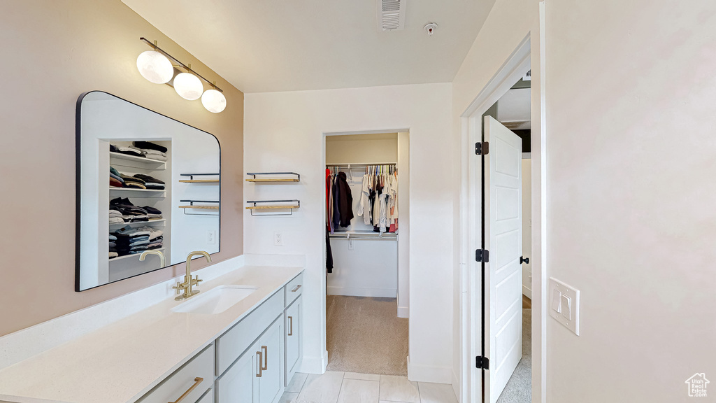 Bathroom with a spacious closet, vanity, and tile patterned floors