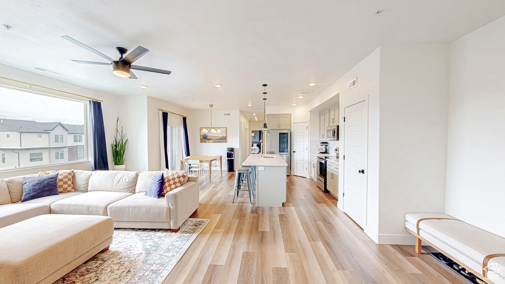 Living room with light wood-style flooring, a ceiling fan, and recessed lighting