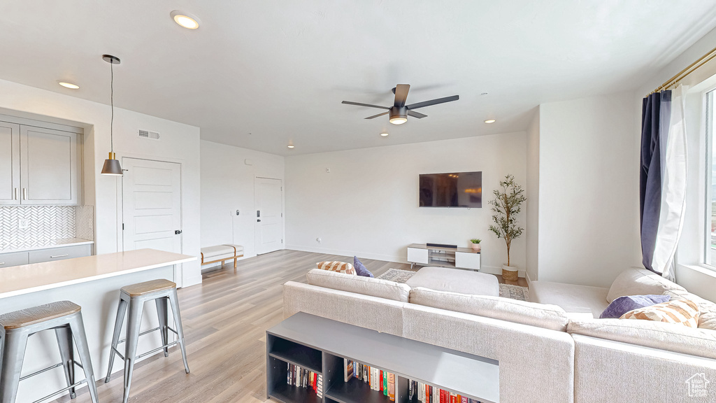 Living area featuring a ceiling fan, recessed lighting, light wood-type flooring, and baseboards