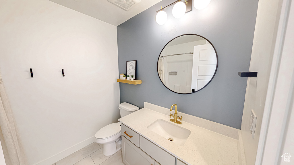 Bathroom with toilet, vanity, and baseboards